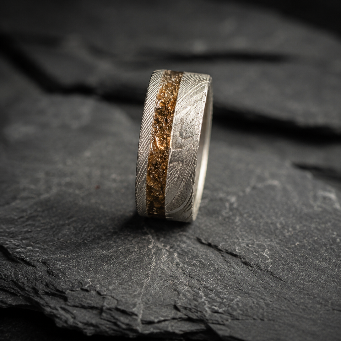 A textured silver ring with a central dinosaur inlay, displayed on a dark slate surface.