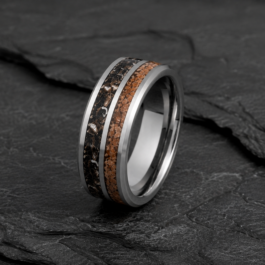 A polished silver-toned ring with two inlays, one black wood grain and one copper-brown wood grain, displayed on a dark slate surface.